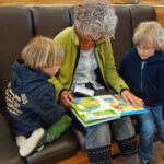 Babcia czyta wnukom książeczkę w czytelni Gręboszów