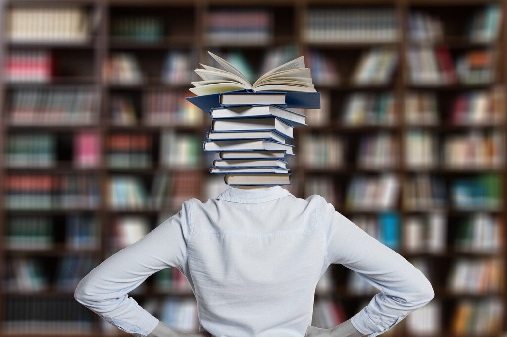 Na zdjęciu znajduje się osoba w bibliotece z książkami zamiat głowy